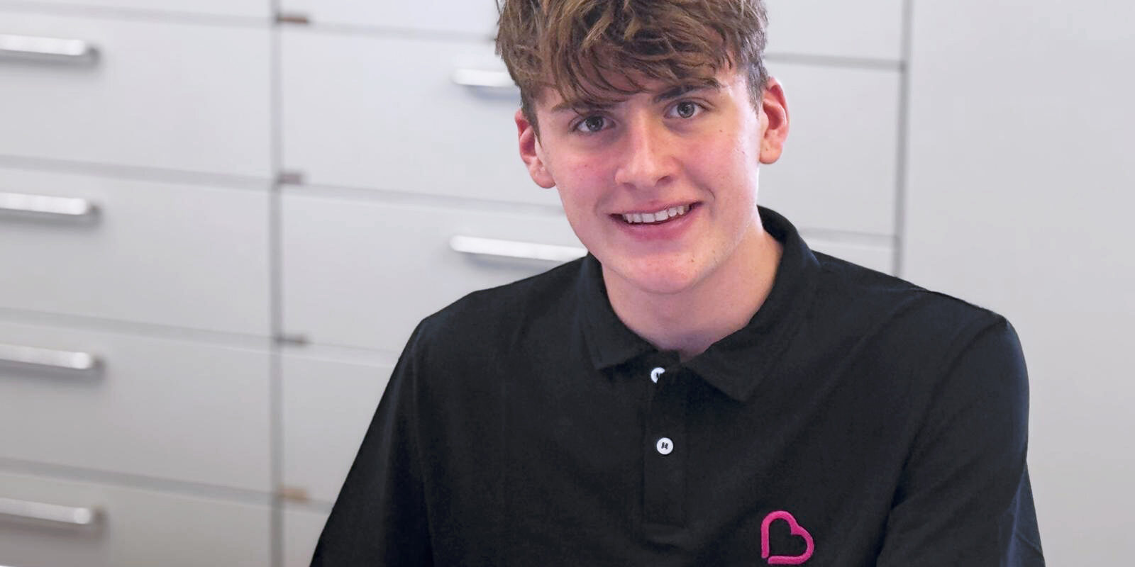 Wilhelm Böckenhoff, ältester Sohn von Alexandra Böckenhoff, unterstützt in der Frauenarztpraxis Böckenhoff in Schweinfurt. Er trägt ein Polo-Shirt mit Praxislogo und unterstützt das Team ab Dezember beim Scannen und Archivieren von Befunden.