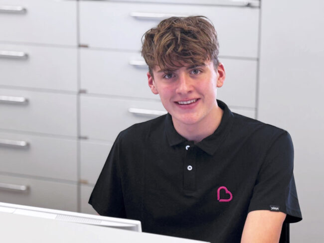 Wilhelm Böckenhoff, ältester Sohn von Alexandra Böckenhoff, unterstützt in der Frauenarztpraxis Böckenhoff in Schweinfurt. Er trägt ein Polo-Shirt mit Praxislogo und unterstützt das Team ab Dezember beim Scannen und Archivieren von Befunden.